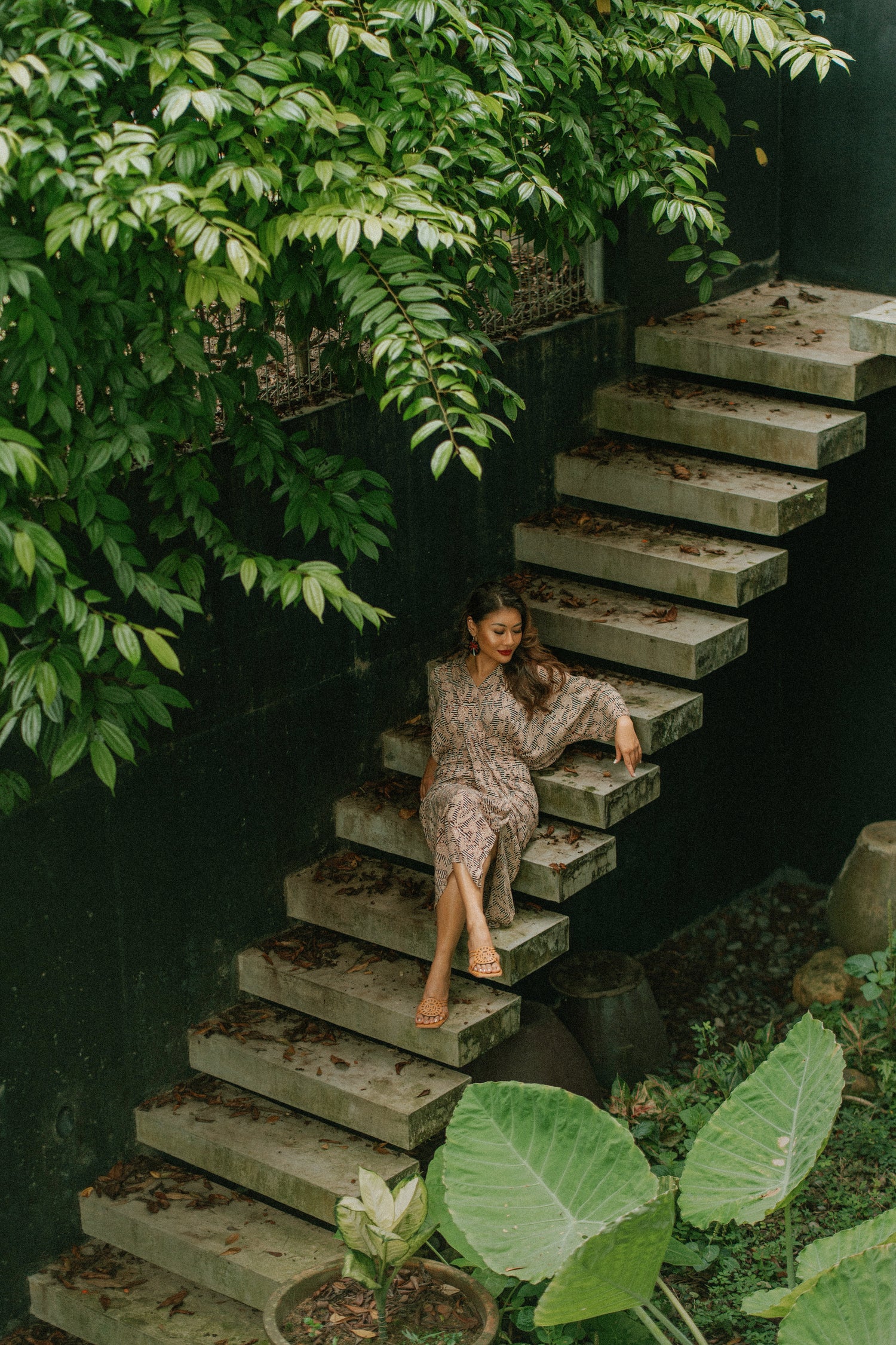 Woman sitting on a set of concrete stairs surrounded by greenery
